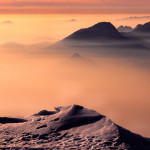 Agosto 2014 - Tramonto invernale dipinto di rosa sulla Pianura Padana, visto dalla cresta meridionale del Monte Baldo. Uno strato di nebbia avvolge la Pianura, e si infila anche nelle vallate del bresciano e sul Lago di Garda. Le vette più alte si ergono verso il cielo come fossero isole in un candido mare.