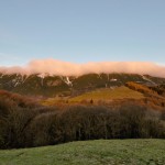 Novembre 2014 - Nella bellissima foto di Diego Bortignon, scatta il 23 novembre alle ore 07:30 da Novezzina, vediamo che le cime del versante orientale del Monte Baldo sono ricoperte da uno strano strato nuvoloso. Si tratta di banner clouds, nubi orografiche che si formano sottovento alla cresta principale di una catena montuosa quando il vento è perpendicolare ad essa. Il vento occidentale presente in quota quel giorno, infatti, ha provocato una zona di turbolenza ad est del Baldo (rotore) causando una regione di sollevamento proprio subito sotto alle cime del Baldo. L’umidità presente all’interno di tale zona di correnti ascendenti condensando ha dato origine alla nube.