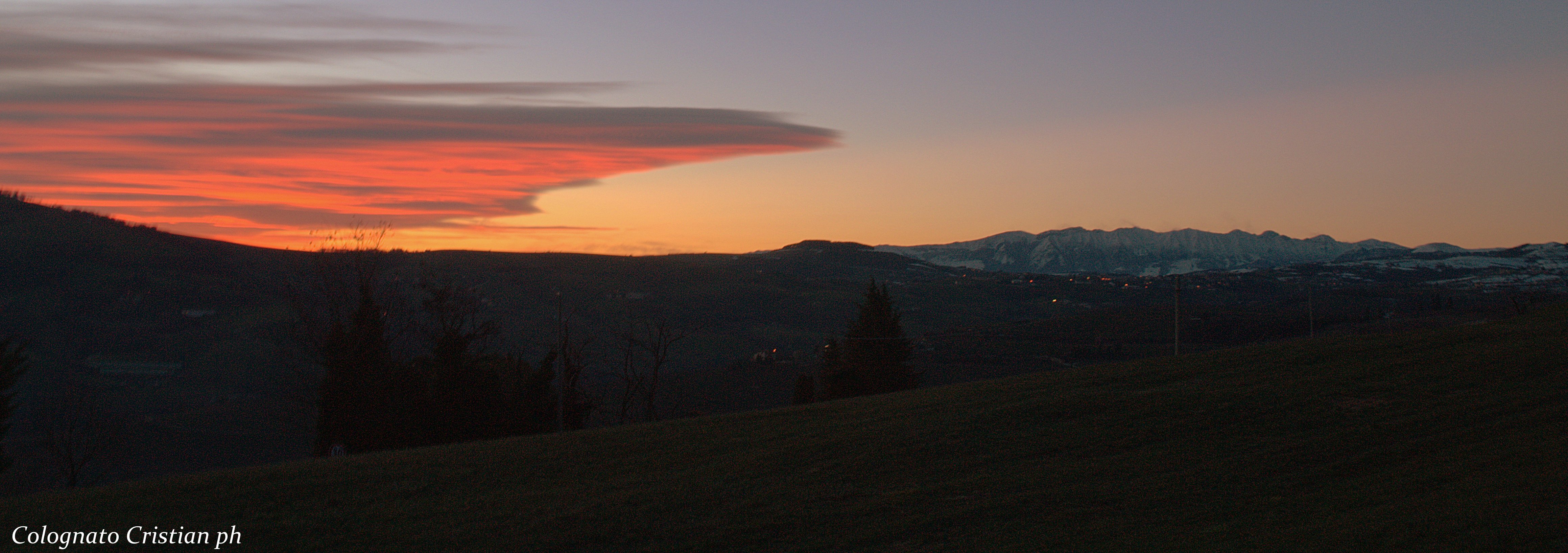 Febbraio 2015 - Nella foto di Cristian Colognato, scattata domenica 8 febbraio dalla Lessinia, si vede uno strato nuvoloso che si estende subito a sud del Monte Baldo. Si tratta di un’onda orografica formata da nubi da sottovento, chiamate anche nubi lenticolari o lee-clouds. Si formano quando intense correnti da Nord impattano sull’arco Alpino causando un’onda in atmosfera. Se vi sono particolari condizioni di umidità e stabilità atmosferica sottovento alla catena alpina, l’aria viene spinta verso l’alto in una zona stazionaria subito a sud delle montagne, dove la condensazione crea la nuvolosità che vediamo nella foto.