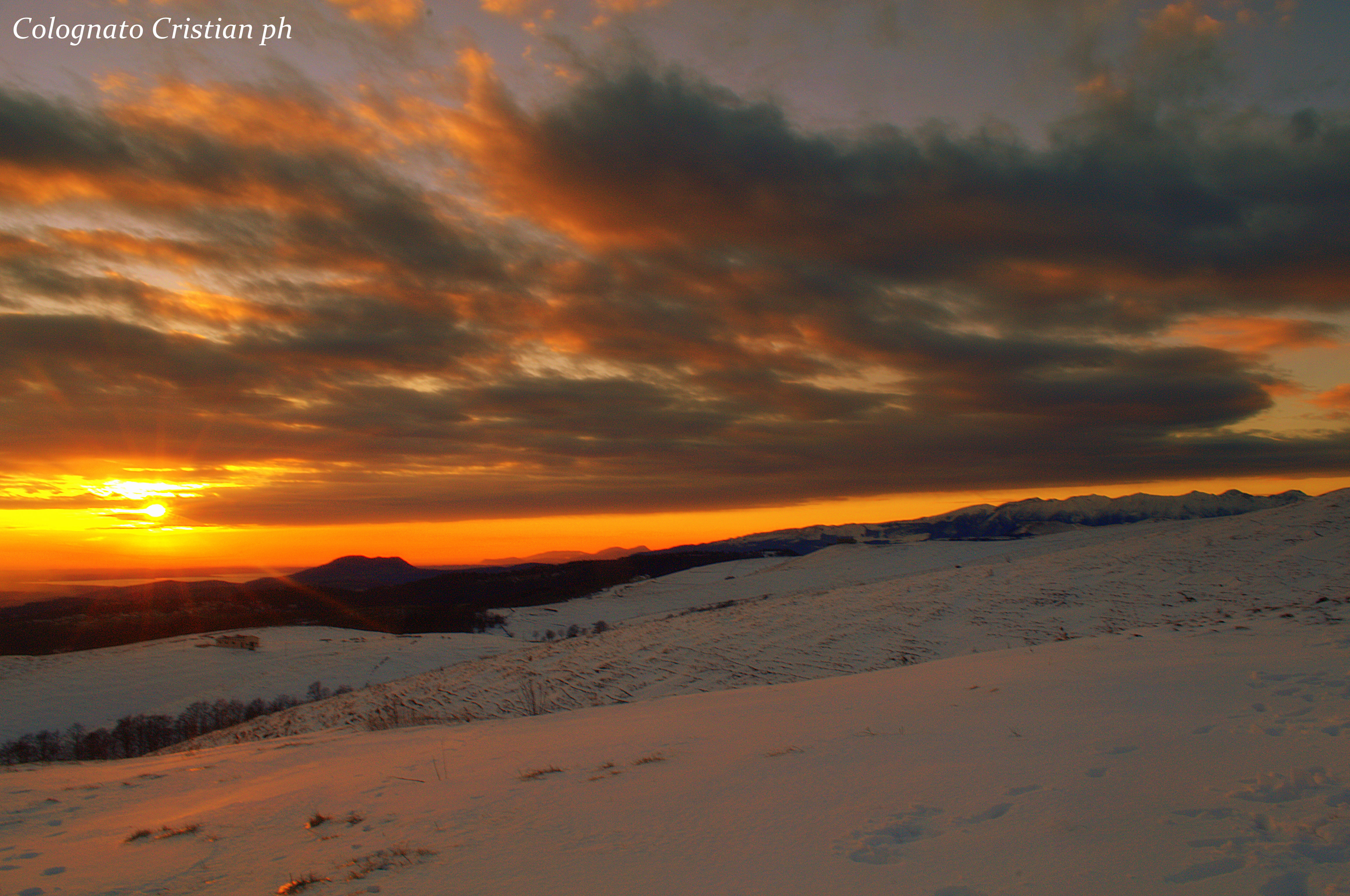 Gennaio 2015 - Nella foto di Cristian Colognato, il tramonto del 25 gennaio da San Giorgio verso Sud-Ovest. Il sole illumina il basso Lago di Garda e l’altipiano della Lessinia, facendosi spazio tra strati nuvolosi. il Monte Baldo, a destra nell’immagine, resta a guardare.