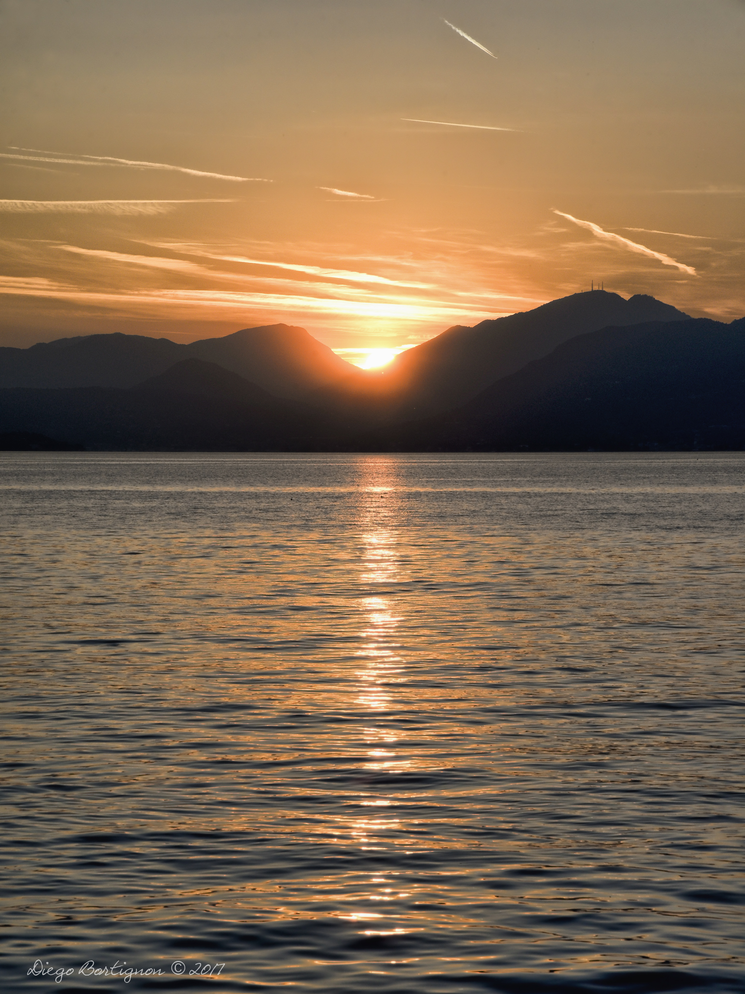 Settembre 2017 - Diego Bortignon ci regala questo scatto al tramonto dal Lago di Garda, in cui il riflesso della luce del sole tra l'acqua del lago, i cirri e cirrostrati e i contrails la fanno da padrone.